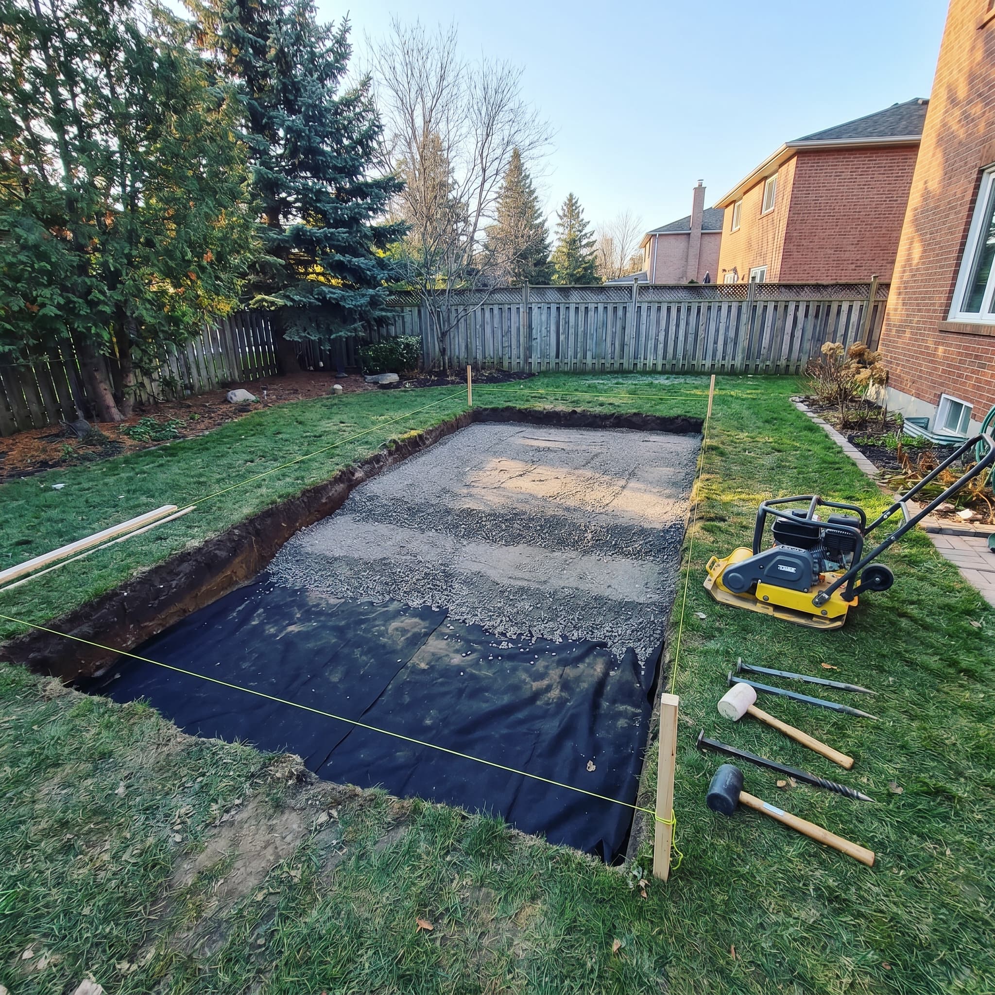 Drainage trench rough-in with perforated weeping tile and clear stone on a backyard hardscape project in Oakville by McCoy Landscape Group